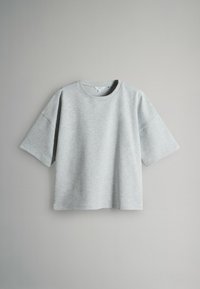 Světlé šedé cropped sweatshirt s krátkým rukávem a kulatým výstřihem zavěšené na jednoduchém šedém pozadí.