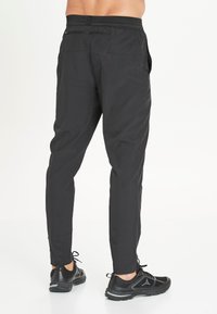 Schwarze Sporthose mit taillierter Passform, elastischem Bund und zwei Seitentaschen, aus leichtem, atmungsaktivem Material gefertigt.