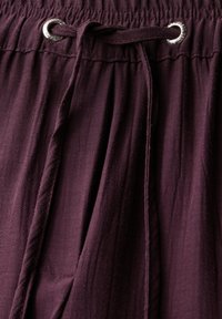 Bordeaux trekbroek met elastische tailleband en zilveren oogjes, gemaakt van zacht stof en voorzien van een subtiel gemêleerd patroon.