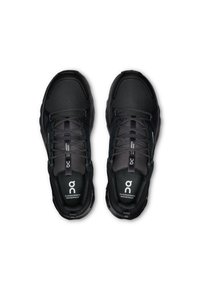 Chaussures de sport noires imperméables avec une tige en mesh texturé, présentées avec un design à lacets, une semelle rembourrée et un logo de marque.