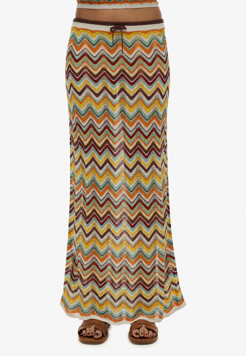 Jupe maxi avec un motif zigzag multicolore dans des tons terreux. Fabriquée en tissu doux et léger avec une taille à cordon ajustable.