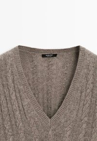 Maglione grigio lavorato a maglia con scollatura a V, con motivi a treccia e bordi a coste. Etichetta che riporta "Massimo Dutti." Texture morbida.