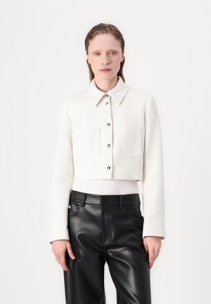 Cropped white textured jacket with a collar, front button closure, and two chest pockets, paired with black leather trousers.