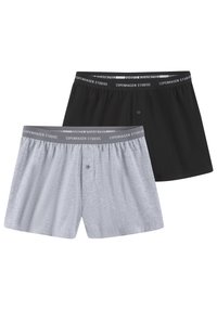Boksershorts i lys grå og sort bomull; elastisk linning med "Copenhagen Studios." Frontknappdetalj på den grå modellen.