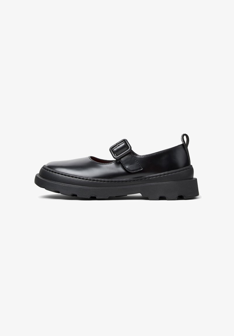 Chaussure Mary Jane en cuir noir avec semelle en caoutchouc épaisse, bride avec boucle réglable et languette à l'arrière, vue de profil sur fond blanc.