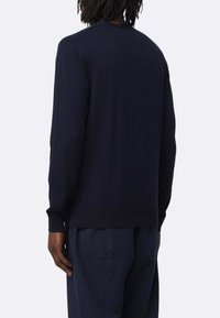 Maglione blu navy con maniche lunghe, scollo rotondo e polsini a coste. Il tessuto sembra morbido con una superficie liscia. Semplice, senza motivi visibili.