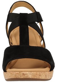 Sandale compensée en daim noir avec un design à brides croisées, semelle en liège et semelle intérieure lisse de couleur beige. Tige texturée pour une meilleure adhérence et un style soigné.