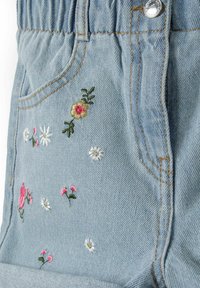 Denim šortai, pasižymintys šviesiai mėlyna medžiaga su rožinėmis, baltomis ir auksinėmis gėlėmis siuvinėjimu. Turi kišenes ir elastinį juosmenį patogumui.