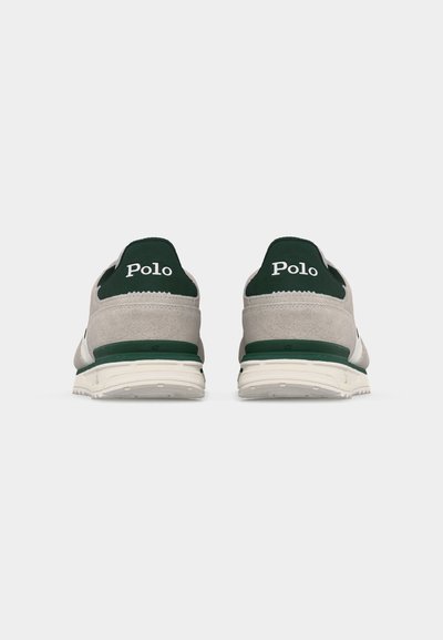 Paire de baskets beige et vert foncé avec semelles blanches, vue de dos, arborant le mot "Polo" sur les languettes du talon.