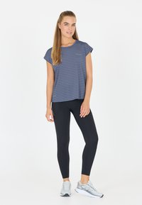 Grårandig kortärmad skjorta i kombination med svarta leggings och ljusgrå sportskor. Slätt tyg med en avslappnad passform.