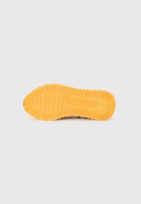 Semelle extérieure en caoutchouc de couleur jaune avec un motif de grip texturé, présentant un tread en zigzag pour l'adhérence et une section centrale lisse.