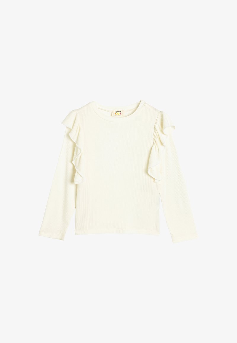 Pitkähihainen ribbikuvioitu paita off-white-värissä, jossa on kerrokselliset volangikoristeet yhdellä olkapäällä. Ominaisuuksiin kuuluu pyöreä pääntie ja suora helma.