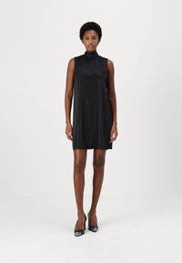 Svart ärmlös klänning med hög krage, med en texturerad tyg och subtila glittrande detaljer, som slutar ovanför knäet.