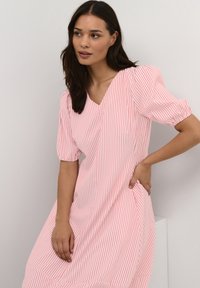 Light pink striped dress with a V-neck, short puff sleeves, and a relaxed fit. Soft fabric, knee-length with side pockets and subtle pleating details.