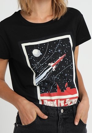 Schwarzes T-Shirt mit rotem und weißem Raketenstart in einen sternenklaren Himmel, Halbmond und roter Stadtsilhouette am unteren Rand.