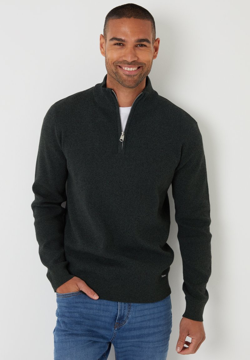 Donkergroene pullover trui met een halve rits, gemaakt van textuurstof. Aansluitend ontwerp met geribde manchetten en zoom, gedragen over een wit shirt.
