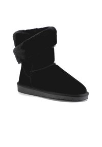 Botines de ante negro con un puño de piel sintética doblado, punta redonda y suela de goma; las texturas contrastan con elementos suaves y esponjosos.