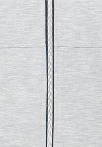 Felpa grigia con zip, caratterizzata da una cerniera argentata, rifiniture blu navy a contrasto lungo la cerniera e un tessuto morbido e testurizzato.