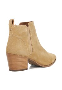 Tan suede ankle boot with a slightly pointed toe, elastic side panels, and a stacked wooden heel. Features a small logo detail on the back.