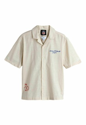 Smėlio spalvos trumpomis rankovėmis susegama marškiniai su NFL logotipu ant apykaklės vidinės pusės, tekstu „National Football League“ ant krūtinės ir užrašu „Est. '20“ apačioje priekyje.