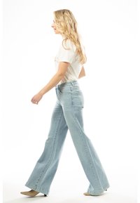 Hellblaue weit geschnittene Jeans aus Denim, mit hoher Taille und dezenten Steppnähten, kombiniert mit einem schlichten weißen T-Shirt.