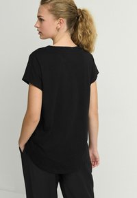 Zwarte korteklauw t-shirt van katoen, met een ronde onderrand en een comfortabele pasvorm, met een frisse, eenvoudige uitstraling.