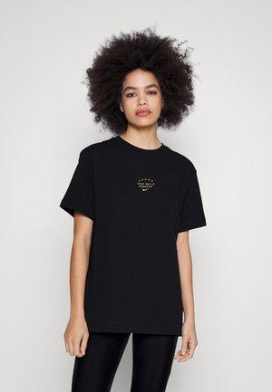 T-shirt noir en coton à manches courtes, avec un graphique doré "JUST DO IT MMXXIII" et le logo Nike sur la poitrine. Col rond simple.