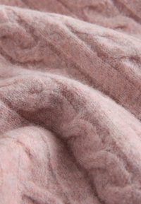 Morbido tessuto rosa lavorato a maglia con una texture soffice e motivi a treccia visibili in primo piano.