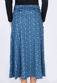 Der blaue Blumenrock zeichnet sich durch ein fließendes Design mit gerafftem Taillendetail aus. Er besteht aus einem weichen Stoff und zeigt kleine blaue Blumen auf einem dunkelblauen Hintergrund.