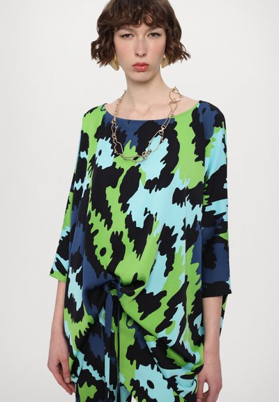 Weites, fließendes Oberteil mit einem auffälligen abstrakten Muster in Grün, Blau und Schwarz. Verfügt über einen U-Boot-Ausschnitt und eine Taillenbindung.