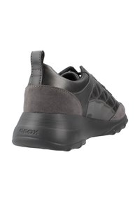 Deportivas negras de hombre con una combinación de cuero liso y ante, un talón texturizado y un patrón geométrico en el lateral. Marca Geox visible.