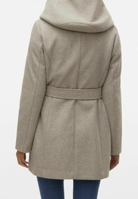 Vaaleanharmaa, vyöllä varustettu takki, jossa on suuri huppu ja istuva siluetti. Siinä on sileä pinta ja näkyvät saumat takana ja hihoissa.