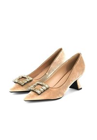 Tacones bajos de ante beige con puntera afilada, decorados con hebillas de strass cuadradas y tacones negros en forma de cono.