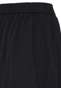 Ceinture élastique noire avec détail de tissu plissé froncé sur un pantalon ou une jupe légère et fluide.