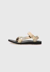 Sandaler med mønstrede stoffreimer i lys grønn og beige på en svart teksturert såle. Har et støttende design med justerbare reimer.