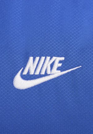 Sinine kuusnurkne kangas, millel on valge tikitud "Nike" logo ja selle all olev nool.