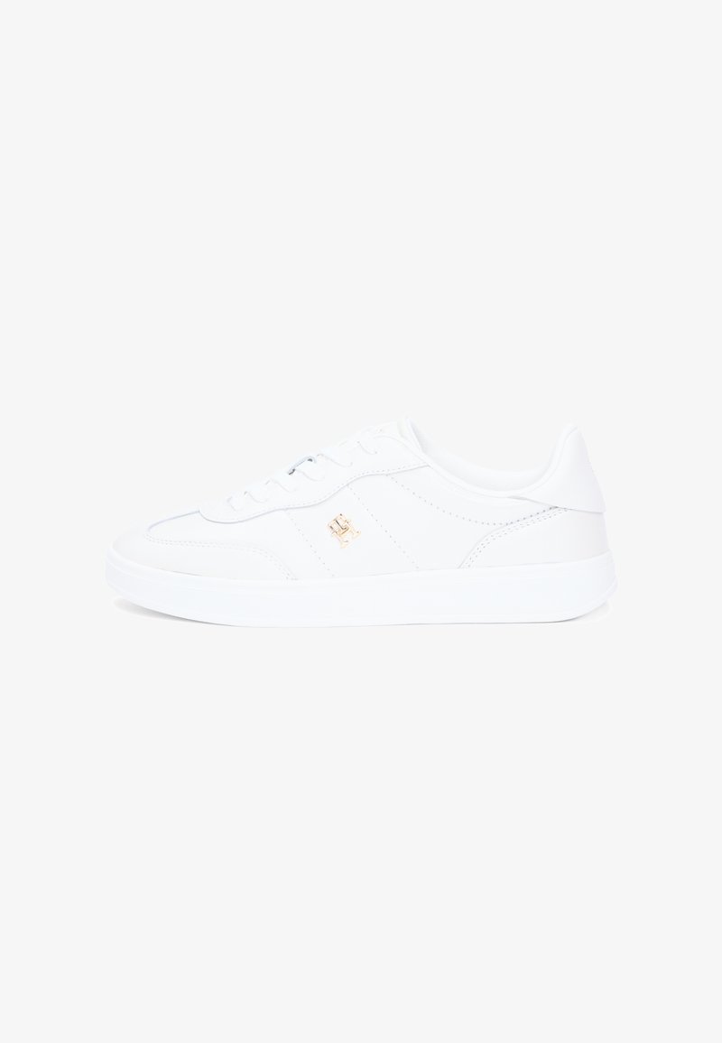 Λευκό αθλητικό παπούτσι με λείο δερμάτινο υλικό, στρογγυλεμένη μύτη και επίπεδη ελαστική σόλα. Διαθέτει διακριτικό ράψιμο και μικρή χρυσή διακοσμητική λεπτομέρεια με λογότυπο.