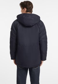 Chaqueta de plumas navy con capucha, puños elásticos y un acabado texturizado. Presenta una costura central en la espalda y bolsillos laterales. Adecuada para climas fríos.