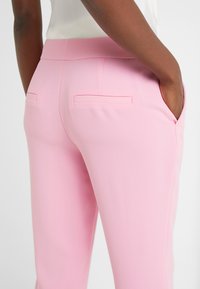 Rosa byxor med en slät yta, slim fit och bakfickor. Midjan är skräddarsydd, vilket framhäver silhuetten.