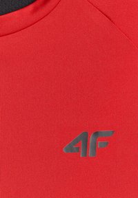 Tissu rouge avec un petit logo noir "4F" imprimé sur la zone de la poitrine d'un vêtement à col rond.
