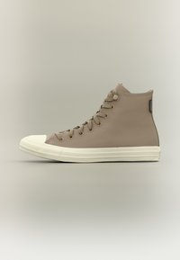 Højtop-sneakers i lyst beige tekstureret materiale med hvid gummisål og tåhætte. Har runde snørebånd og lille logofane på siden.