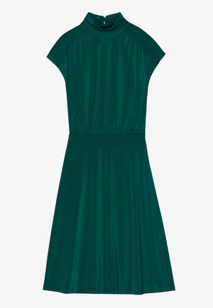 Teal kjole laget av myk, lett stoff. Har høy hals, korte ermer og en utsvingt skjørt, med subtil drapering i midjen.