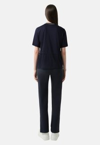 Námořnické modré triko s krátkým rukávem, se slušivým pasem a vysokým výstřihem, spárované se slim fit námořnickými kalhotami a bílými teniskami. Hladká látka, volný styl.