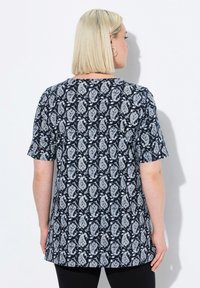 Camiseta de color navy con mangas cortas que presenta un patrón de paisley blanco, escote redondo y un corte relajado, confeccionada con una tela ligera.