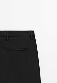 Black trousers with a pinstripe pattern, featuring a flat front, belt loops, and a single back pocket. Smooth fabric texture.