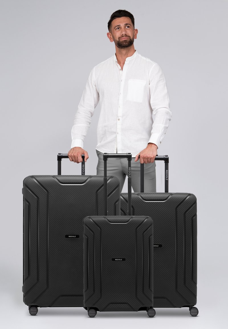 Set van drie zwarte harde koffers met een gestructureerd oppervlak, stevige handgrepen en wielen, met een logo aan de voorkant.