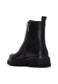 Botín de cuero negro hasta el tobillo con cremallera lateral, suela rugged y tirador. Presenta una textura suave y punta reforzada con detalles de costura mínimos.