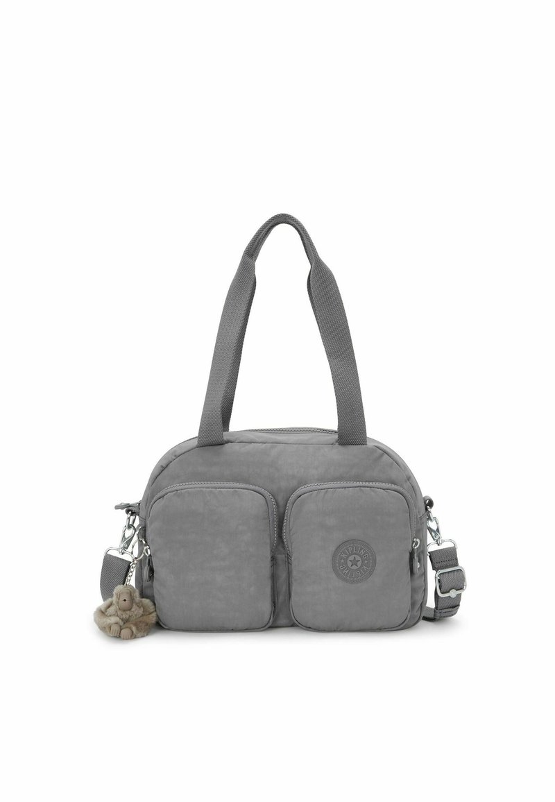 Bolso de tela gris con dos bolsillos frontales, forma redondeada, doble asa, correa ajustable y un pequeño charm de mono adjunto.
