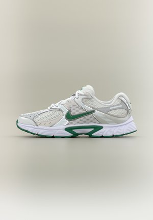 Biało-zielony but do biegania Nike z siateczkowymi panelami, amortyzowaną podeszwą i zielonym logo Swoosh po boku, przedstawiony z profilu.