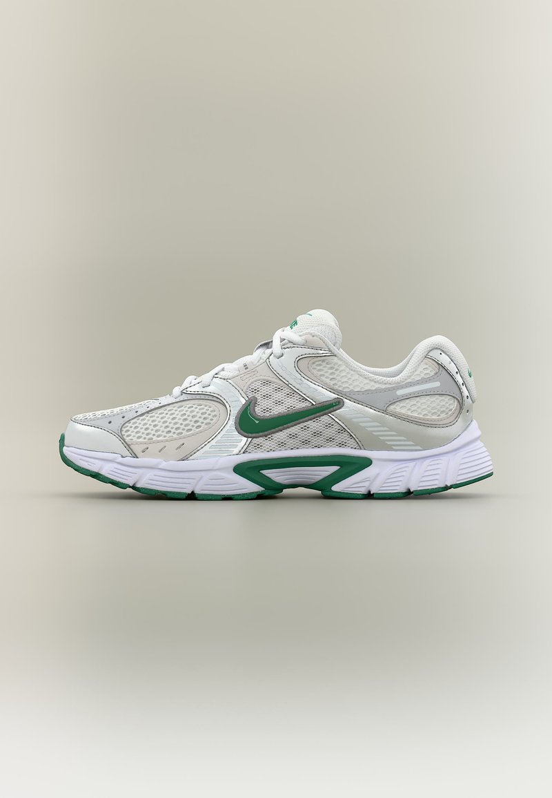 Fehér és zöld Nike futócipő hálós panelekkel, párnázott talppal és zöld pipa logóval az oldalán, oldalnézetben ábrázolva.